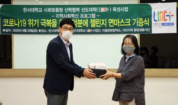 한서대 산학협력단 김현성 단장이 서산시대옹달샘 김영선 단장에게 면마스크를 전달하고 있다.