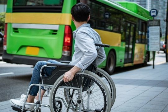 지나치는 버스를 바라보고만 있는 휠체어 장애인