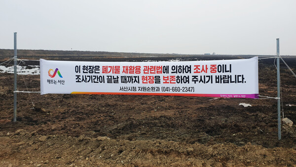 현장 조사를 위해 서산시청 공무원이 부숙토가 뿌려진 농지에 현수막을 게시했다.